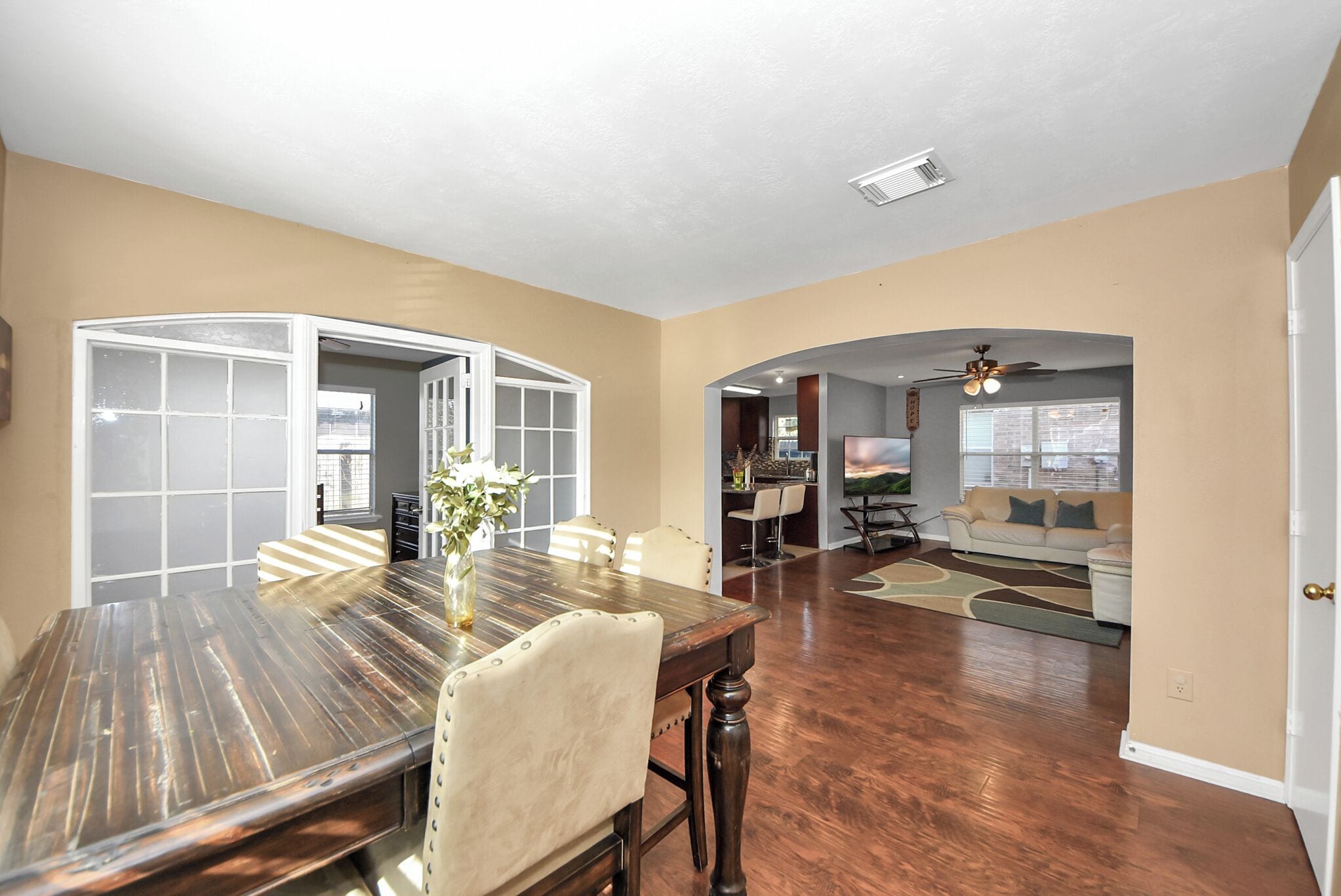 A spacious living room with a dining area, a kitchen, and a seating area with a sofa and chairs.