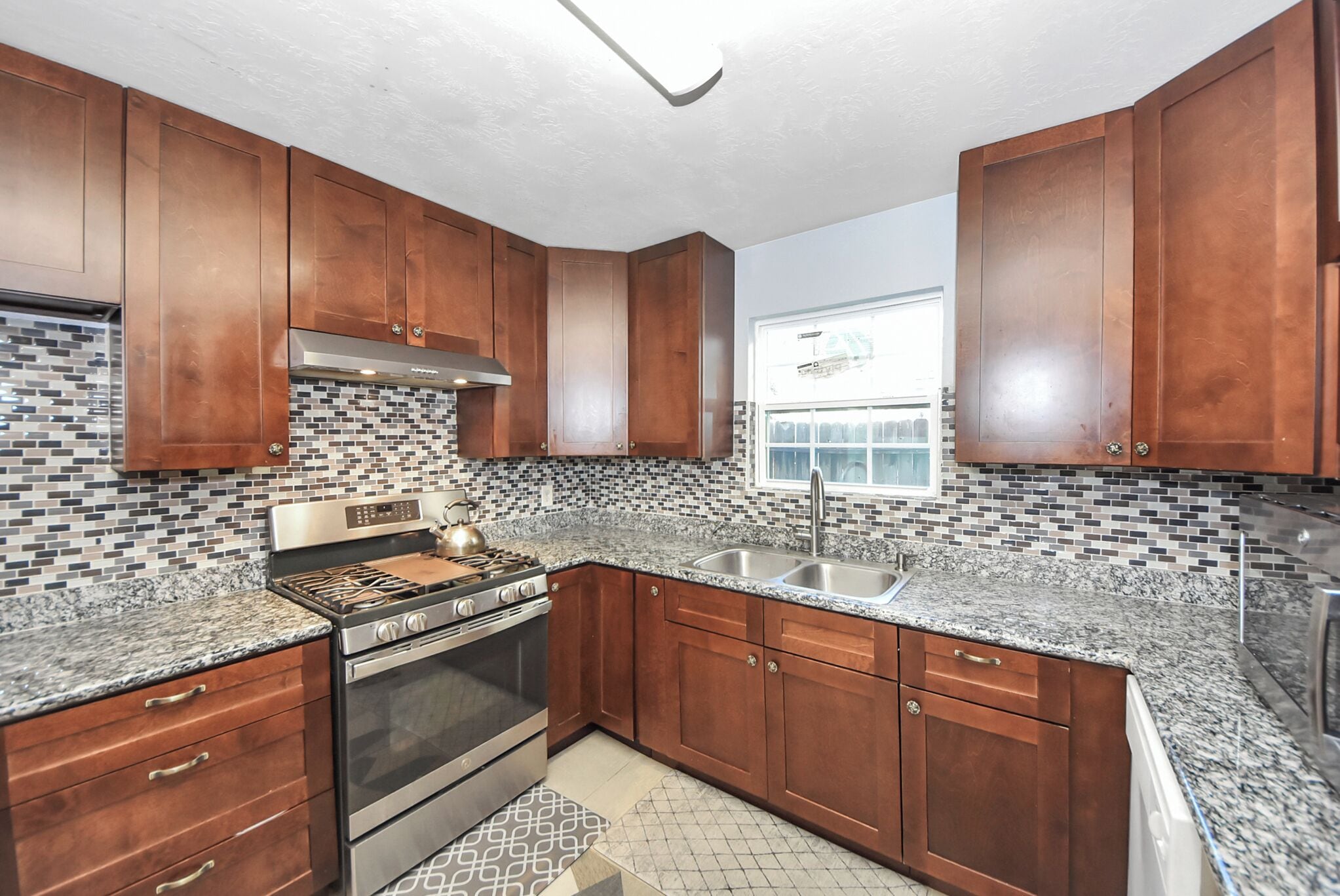 A kitchen with wooden cabinets, a stainless steel stove, and a tiled backsplash.