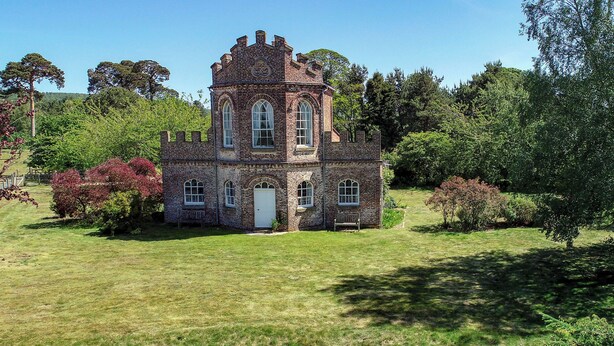A large, historic brick building with arched windows and a central tower, surrounded by lush greenery. - Historic folly in Capability Brown park for family or friends groups (Malton)