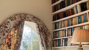 A room with a window, a bookshelf, a lamp, and a chair. - Historic folly in Capability Brown park for family or friends groups (Malton)