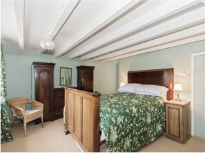 Un dormitorio con una cama de madera, una mesita de noche, una silla y dos cómodas.