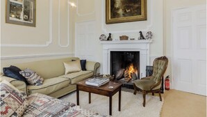 A living room with a fireplace, a sofa, a chair, and a coffee table. - Historic folly in Capability Brown park for family or friends groups (Malton)
