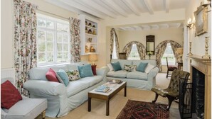 A living room with two sofas, a coffee table, a fireplace, and decorative items on shelves. - Historic folly in Capability Brown park for family or friends groups (Malton)