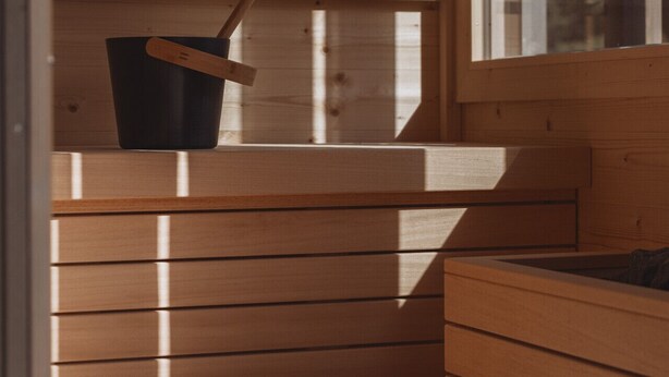 A wooden cabin interior with a bench, a window, and a view of trees. - DAS AICH - Suite Sova (Aich-Assach)