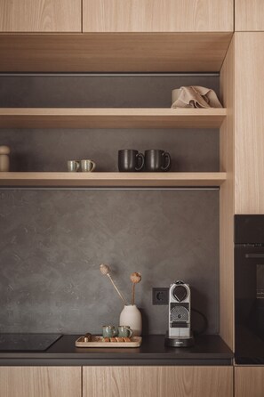 A kitchen with wooden cabinets, a countertop, and a coffee maker. - DAS AICH - Suite Sova (Aich-Assach)