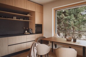Une cuisine moderne avec des meubles en bois, un plan de travail noir et un coin repas comprenant deux chaises et une table.