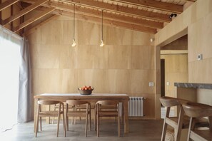 A wooden dining area with a table, chairs, and a fruit bowl.
