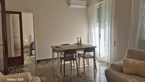 Habitación de hotel con mesa de comedor, sillas, sofá, unidad de aire acondicionado y vista al exterior.