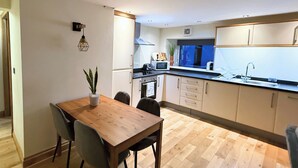 Una cocina moderna con piso de madera, una mesa de comedor con sillas y una planta en maceta.