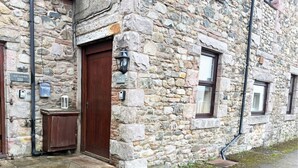 Un edificio de piedra con una puerta de madera, un letrero que dice 'Old Corner Barn' y una ventana con vistas.