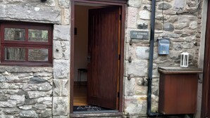 A stone building with a wooden door, a welcome mat, and a sign reading 'Old Corner Barn.' - Old Corner Barn (Penrith)