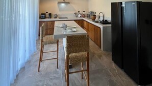 A modern kitchen with a dining area, featuring a large island, pendant lights, and a black refrigerator. - New Beautiful private villa with pool 10 minutes walk from Puerto Viejo. (Puerto Viejo de Talamanca)