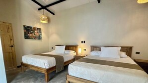 A hotel room with two beds, a wooden door, a painting on the wall, and a ceiling light fixture. - New Beautiful private villa with pool 10 minutes walk from Puerto Viejo. (Puerto Viejo de Talamanca)