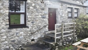 A stone building with a wooden staircase, a door, and windows. - Crag Barn Cottage (Penrith)