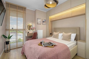 Ein Schlafzimmer mit einem großen Bett, einem Nachttisch, einem Spiegel und einem Fenster mit Jalousien.