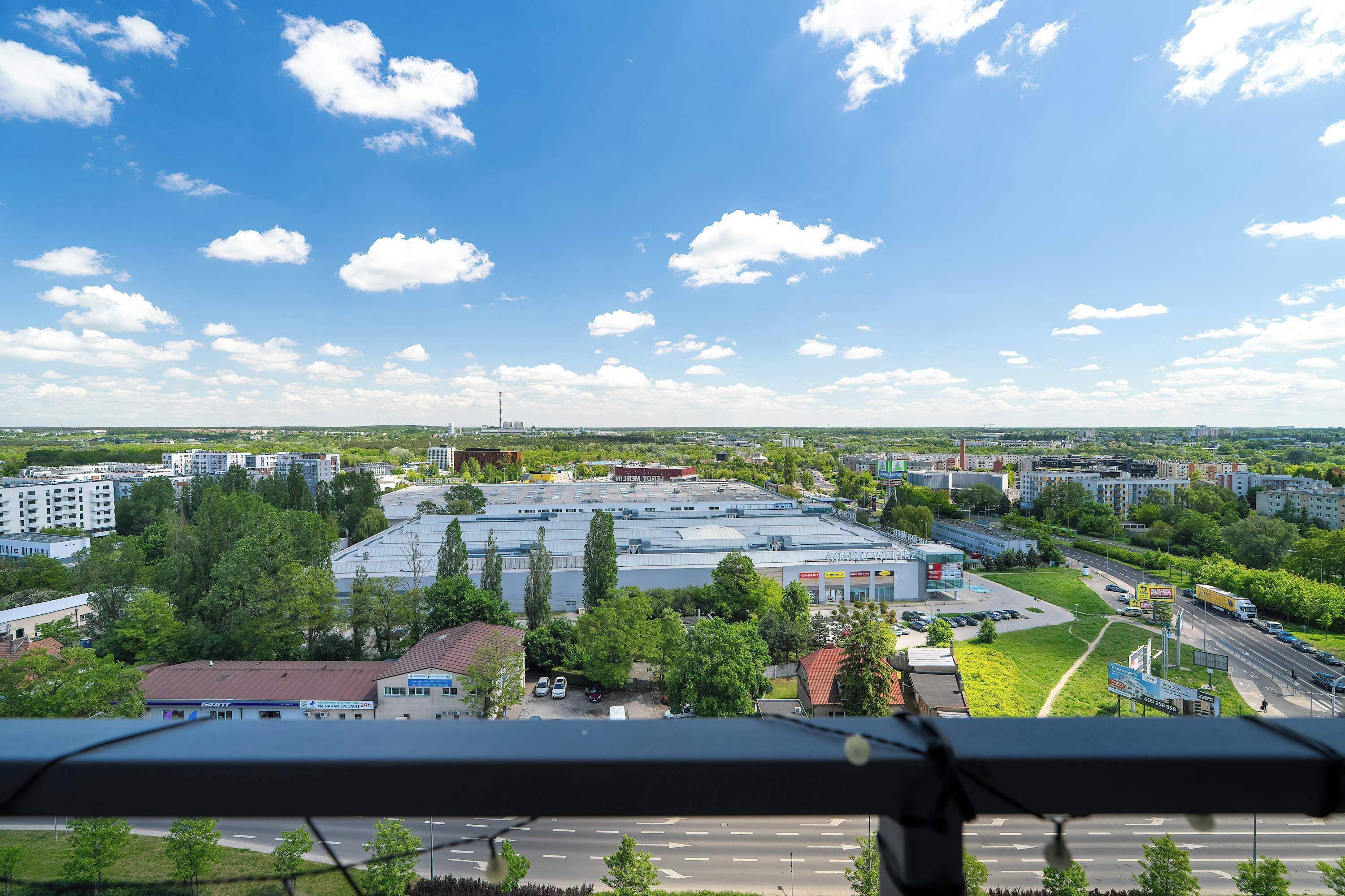 A cityscape with a large industrial building, roads, and greenery.