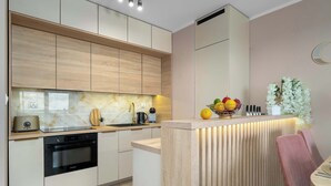 Una cocina moderna con armarios de madera, horno empotrado y una isla central con frutero.