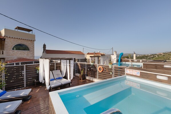 A rooftop pool area with lounge chairs, a small pool, and a view of the surrounding landscape. - Apartment 'Boho' with Mountain View, Wi-Fi and Air Conditioning (Chania)