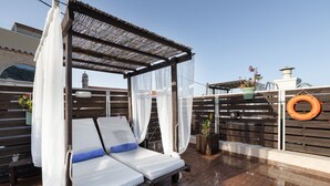 Une terrasse sur le toit avec un lit à baldaquin, une bouée de sauvetage et des plantes en pot.
