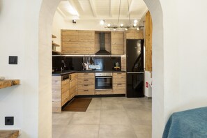 Une cuisine moderne avec des meubles en bois, un four encastré et une hotte de cuisson en acier inoxydable.