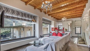 A spacious living area with a high wooden ceiling, a glass table, and a cozy seating area. - Apartment 'Modern' with Mountain View, Wi-Fi and Air Conditioning (Chania)
