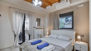 A bedroom with a bed, a nightstand, a window with curtains, a radiator, and a ceiling light fixture. - Apartment 'Modern' with Mountain View, Wi-Fi and Air Conditioning (Chania)