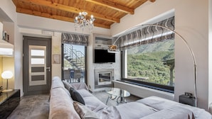 A modern living room with a sofa, a fireplace, a TV, and a large window with a view of greenery. - Apartment 'Modern' with Mountain View, Wi-Fi and Air Conditioning (Chania)