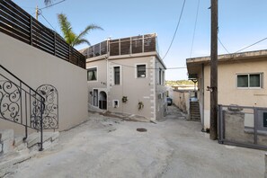 A narrow street with buildings on either side, a metal gate, and a palm tree in the background. - Apartment 'Rustic' with Mountain View, Wi-Fi and Air Conditioning (Chania)