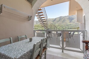 A balcony with a table and chairs, a staircase, and a view of mountains. - Apartment 'Rustic' with Mountain View, Wi-Fi and Air Conditioning (Chania)