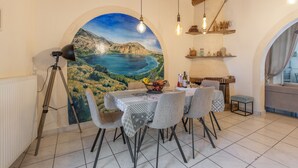 Een eethoek met een tafel voor vier personen, een statief en een landschapsschildering.