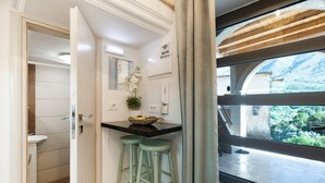 Una cocina con encimera de madera, dos taburetes verdes, un ventanal con vistas a la vegetación y un cartel de Wi-Fi.