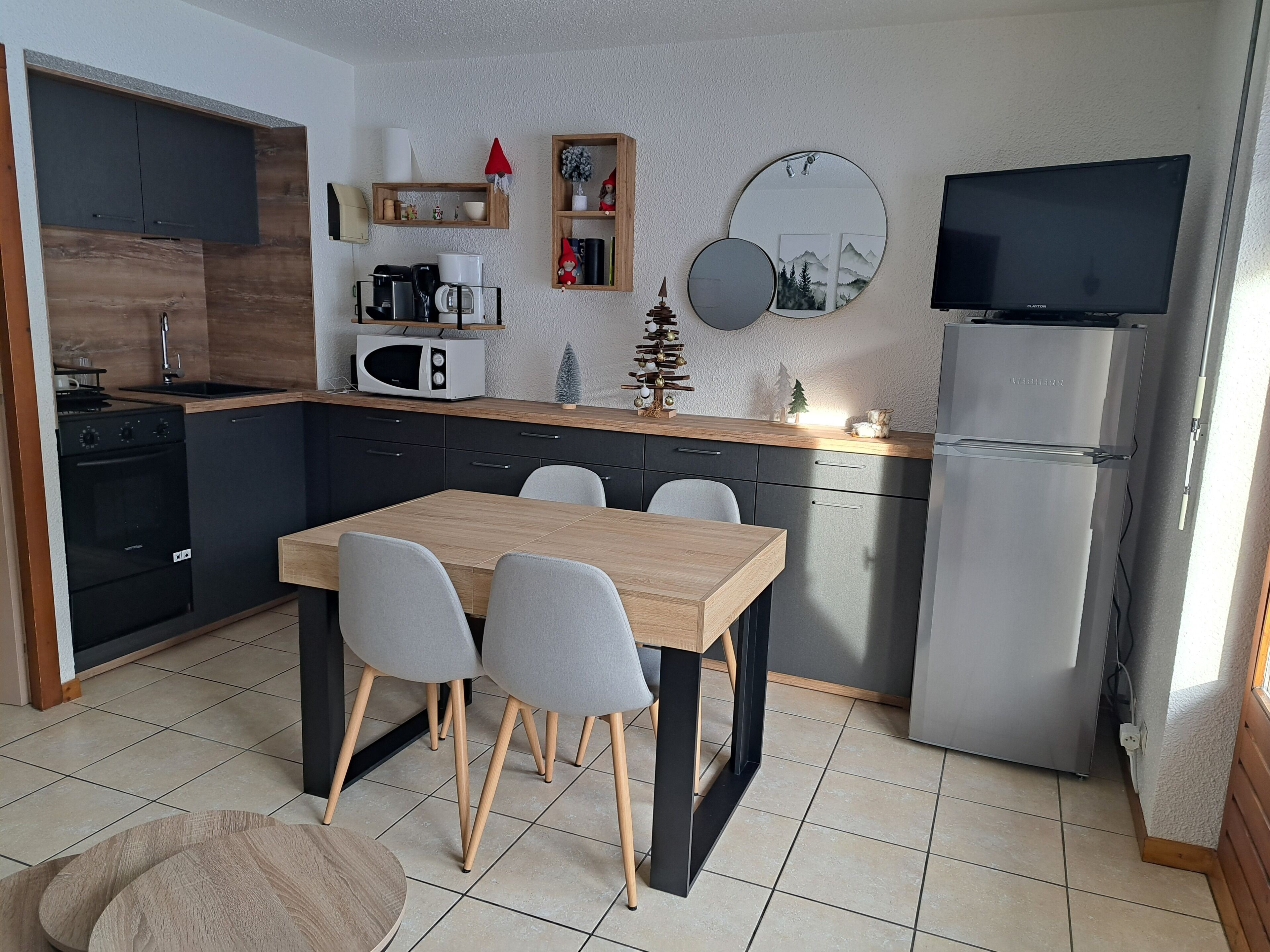 A modern kitchen with a dining table, chairs, a refrigerator, a microwave, and a stove.