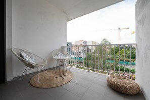 A balcony with two wicker chairs, a small round table, and a woven floor mat. - Breina II by Trip2Portugal (Porto)