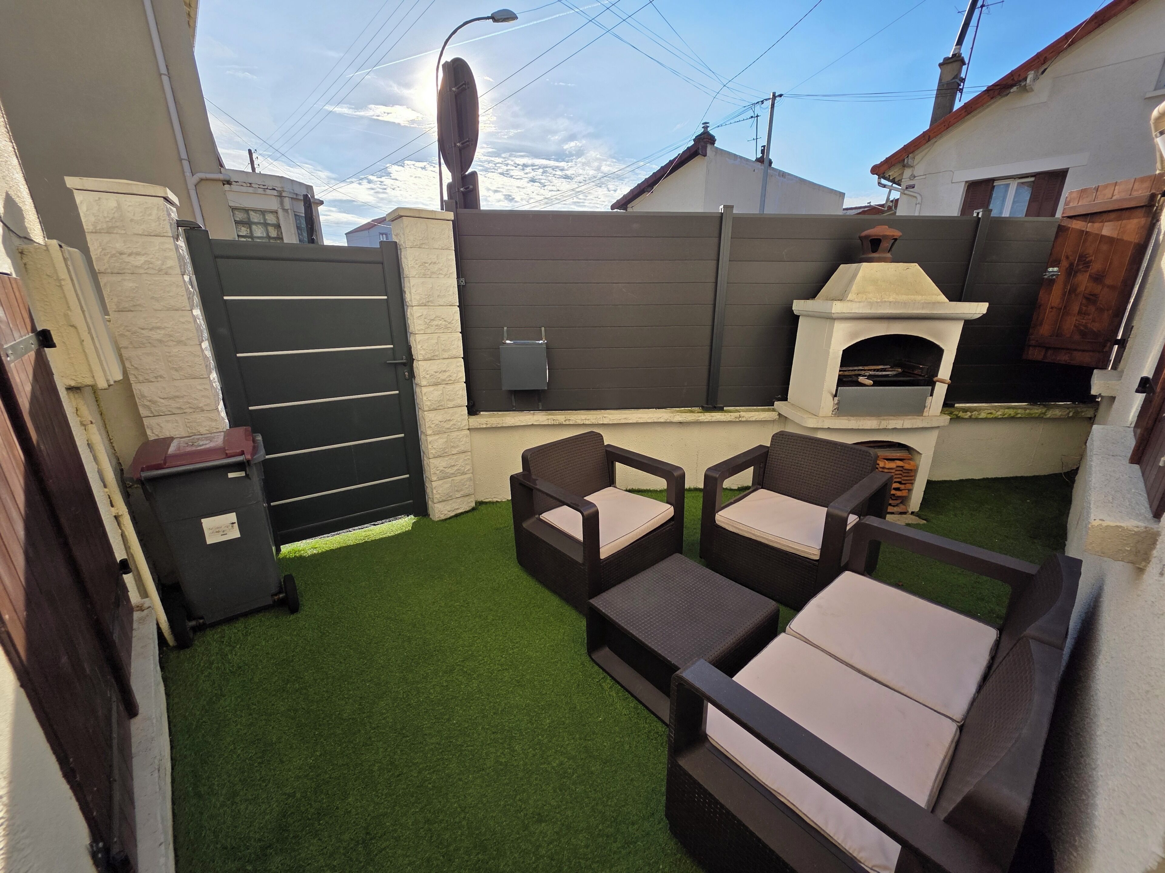 A patio with artificial grass, a grill, and outdoor seating.