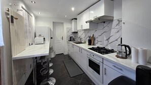 Eine moderne Küche mit weißen Schränken, einem Gasherd, einer Kaffeemaschine und einer Mikrowelle.
