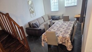 Ein modernes Wohnzimmer mit Sofa, Esstisch und Treppe.