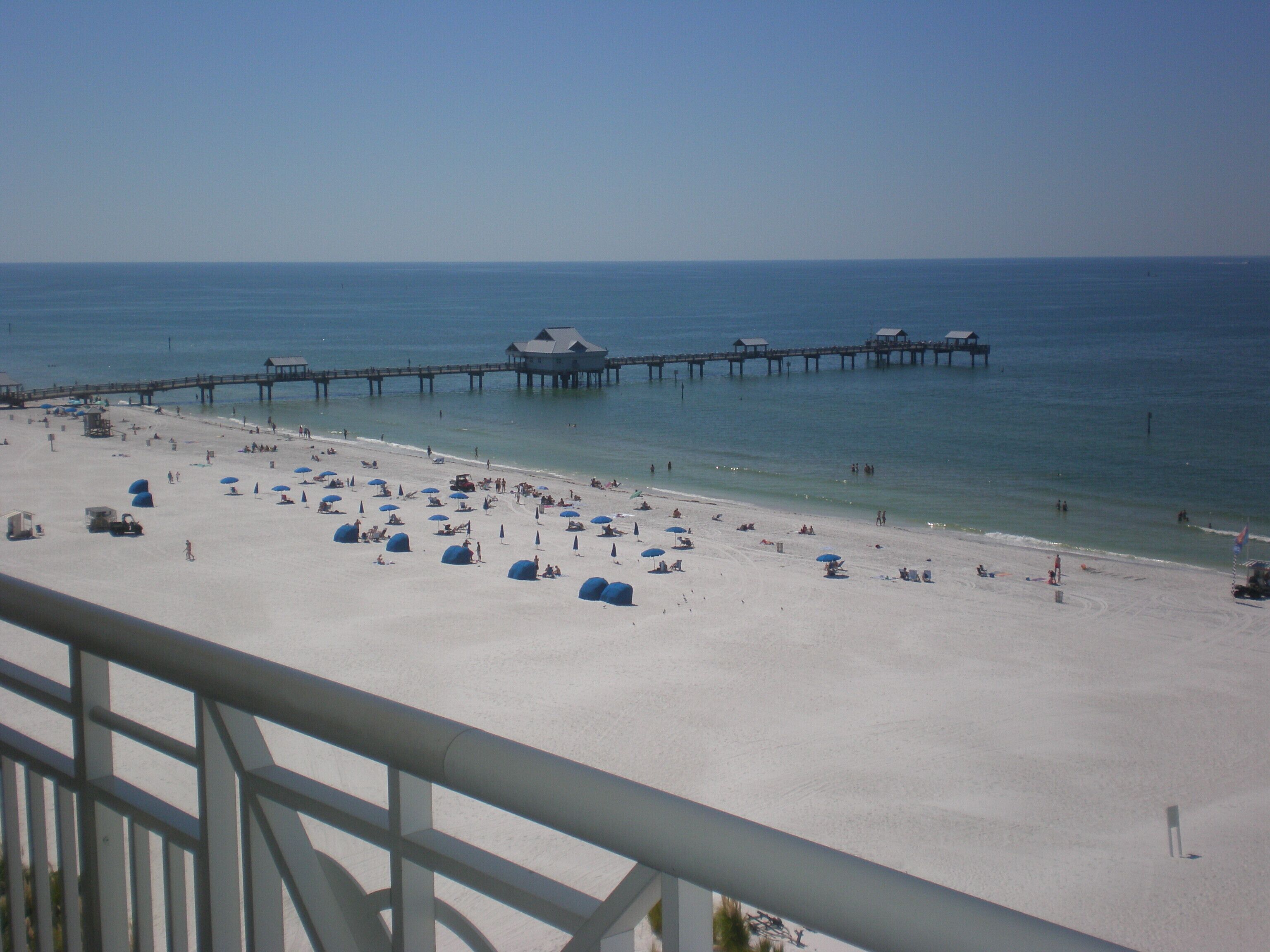 A beach with a pier extending into the water, featuring several buildings.