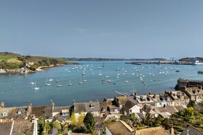 A coastal town with a harbor filled with boats, historic buildings, and a bridge in the distance. - Captains No. 9 (Falmouth)