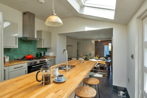 A modern kitchen with a wooden island, stainless steel appliances, and a skylight. - Captains No. 9 (Falmouth)