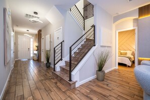 Interior moderno com escada de madeira, corredor a levar a um quarto e zona de estar com um sofá.