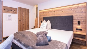 A neatly made bed with a grey headboard, a wooden wall panel, and a small bedside table with a lamp. - Centrally located apartment hotel, right next to the cable car, wellness breakfast (Werfenweng)