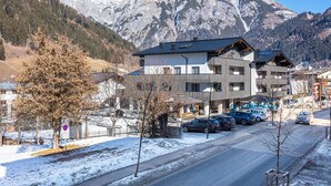 A hotel with a modern design, a parking lot, and a mountain backdrop. - Centrally located apartment hotel, right next to the cable car, wellness breakfast (Werfenweng)