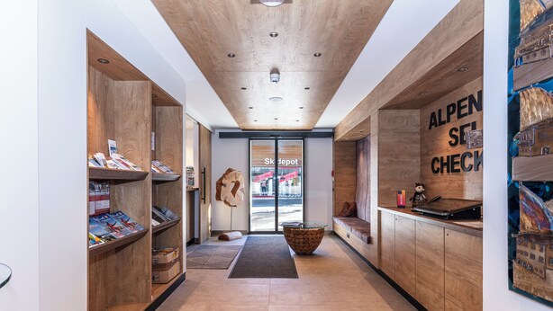 A modern interior with wooden shelving, a central stone table, and a check-in counter. - Centrally located apartment hotel, right next to the cable car, wellness breakfast (Werfenweng)