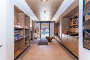 Un intérieur moderne avec des étagères en bois, une table centrale en pierre et un comptoir d’enregistrement.