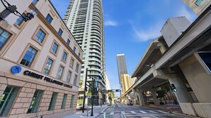Un immeuble à plusieurs étages doté d’une façade incurvée, une rue avec un passage piéton et un feu de signalisation.