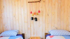 A wooden room with two beds, a small wooden table, and two wall-mounted lamps. - Glamping Tilcara El Obrador (Tilcara)
