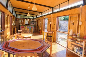 Una habitación amplia con una gran mesa octogonal, muebles de madera y ventanas grandes que dejan entrar luz natural.