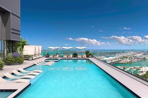 A rooftop infinity pool with lounge chairs and umbrellas, overlooking a cityscape and water. - Miami 165 - One Bedroom Apartment, Sleeps 5 (Miami)