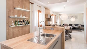 Una cocina moderna con armarios de madera, un lavaplatos empotrado y un comedor con mesa y sillas.