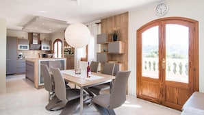 Una cocina moderna con comedor, una puerta de madera con vistas y un reloj en la pared.
